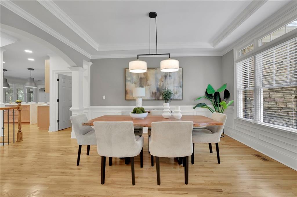 Dining room with a wood table, upholstered chairs, tray ceiling, and large windows.