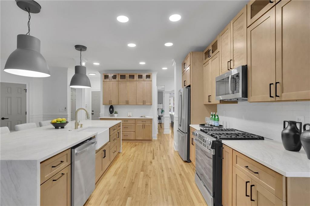 Kitchen with light wood cabinets, a large white island, and stainless steel appliances.