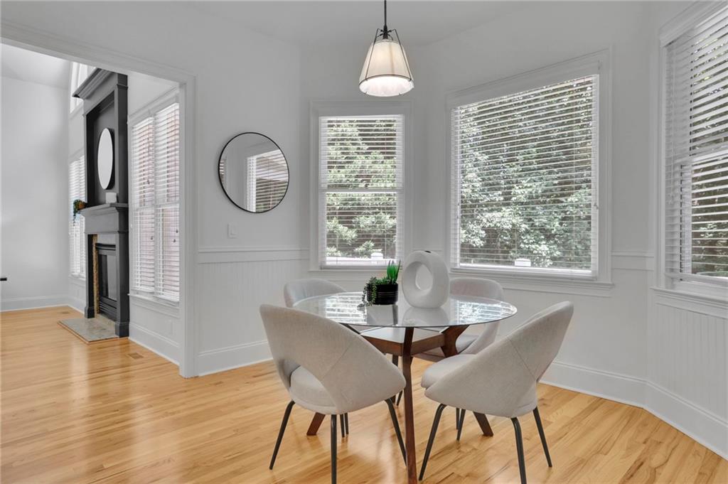 Dining area with a glass-top table, upholstered chairs, large windows, and an adjoining fireplace.