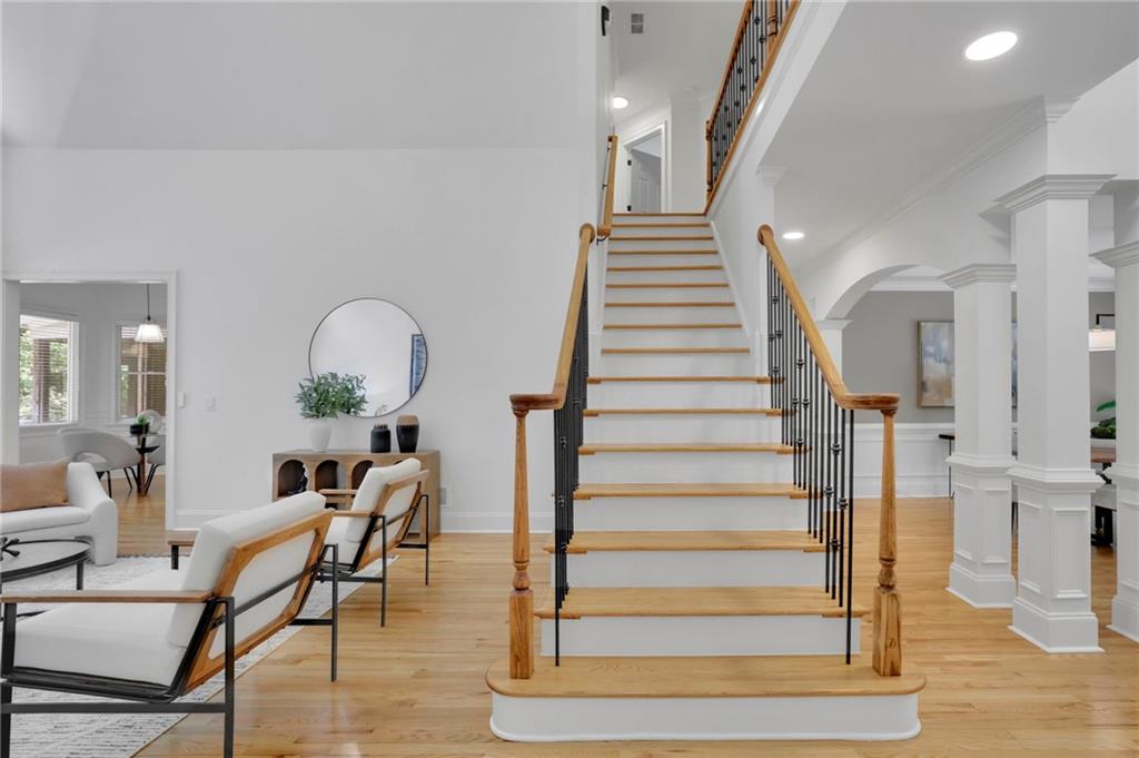 Two-story foyer with a wood staircase, black iron balusters, and light hardwood floors.