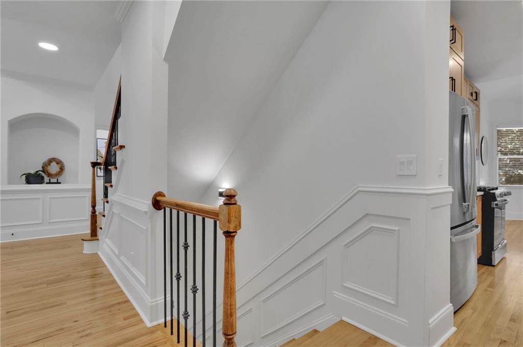 Bright staircase with white paneled walls, light wood floors, and a wood-and-metal railing.