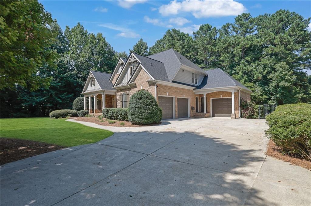 Brick and siding house with multiple gables, two garage doors, and a broad concrete driveway.