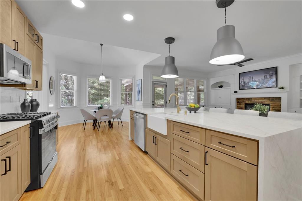 Open-plan kitchen with a white island, light wood cabinets, and dining area beside windows.