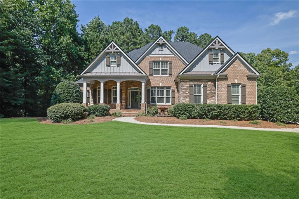 Brick home with stone accents and multiple gables, set behind a broad green lawn.