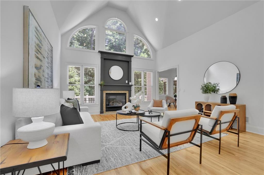 Living room with a fireplace, vaulted ceiling, and tall arched windows.