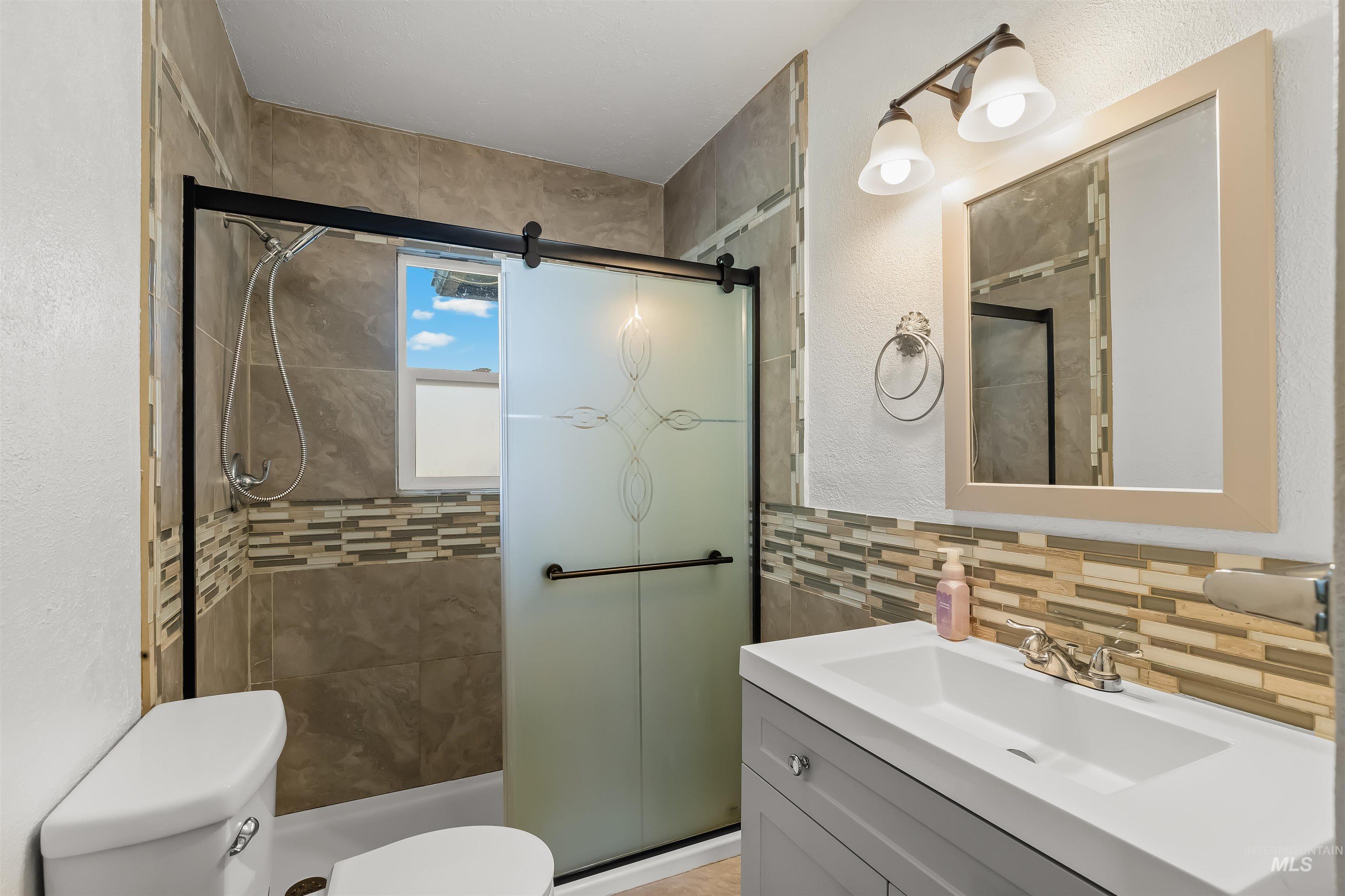 Bathroom with a tiled walk-in shower, frosted glass doors, and a white vanity.