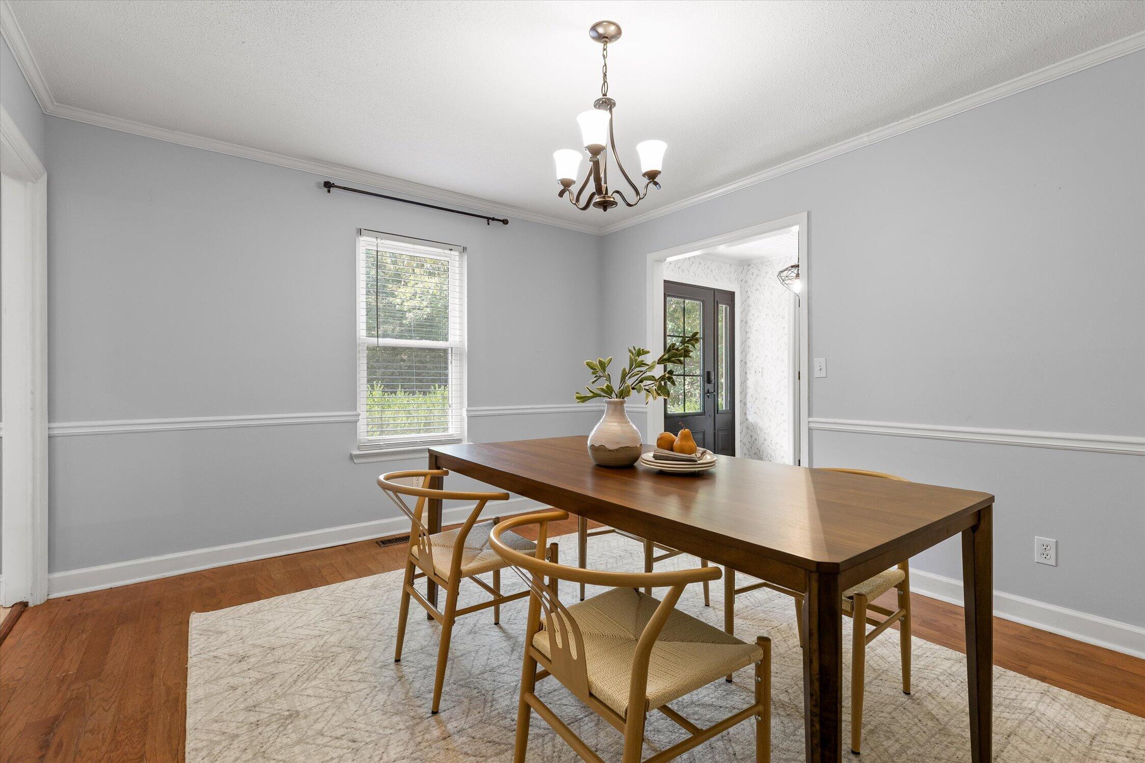 Dining room with a dark wood table, woven chairs, chandelier, and hardwood floors.