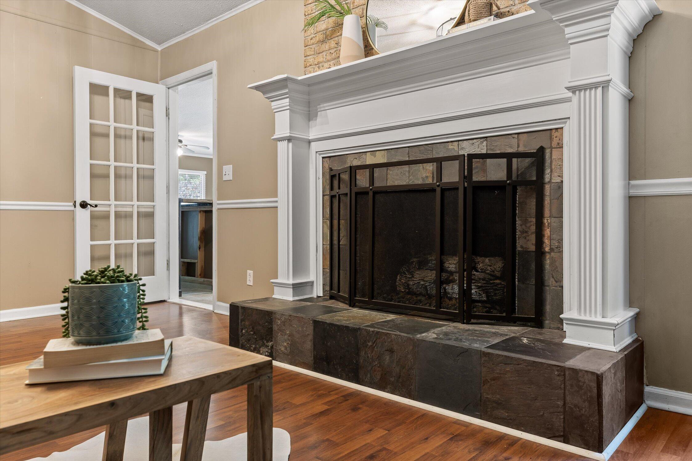 Living room fireplace with a substantial white mantel, stone surround, and black mesh screen.