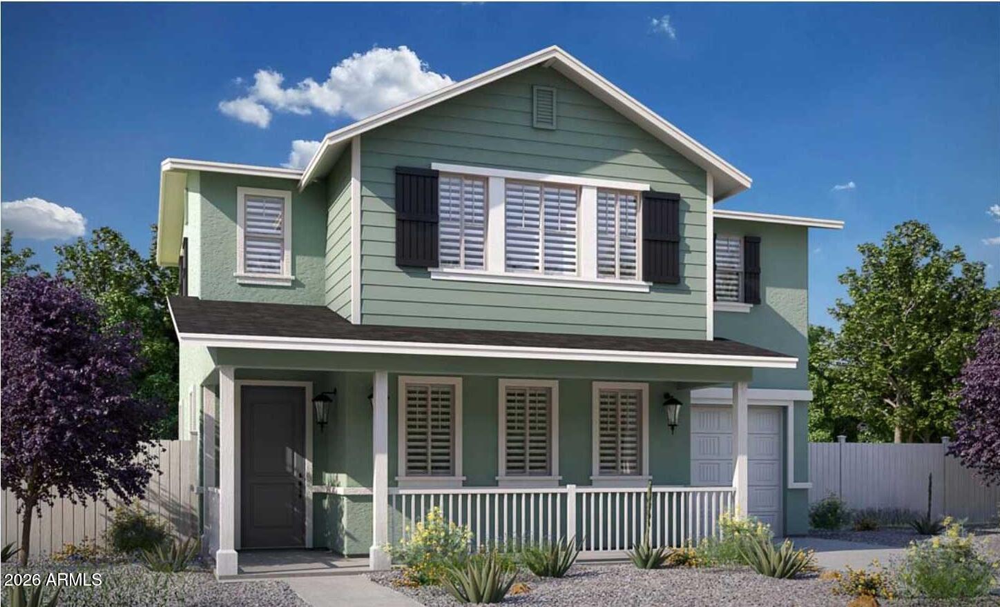 Sage-green two-story house with black shutters, a covered porch, and desert landscaping.