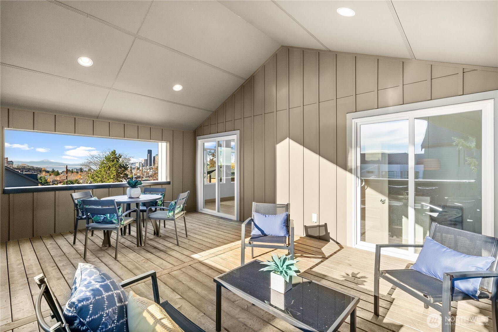 Covered deck with dining and lounge seating, overlooking the Seattle skyline.