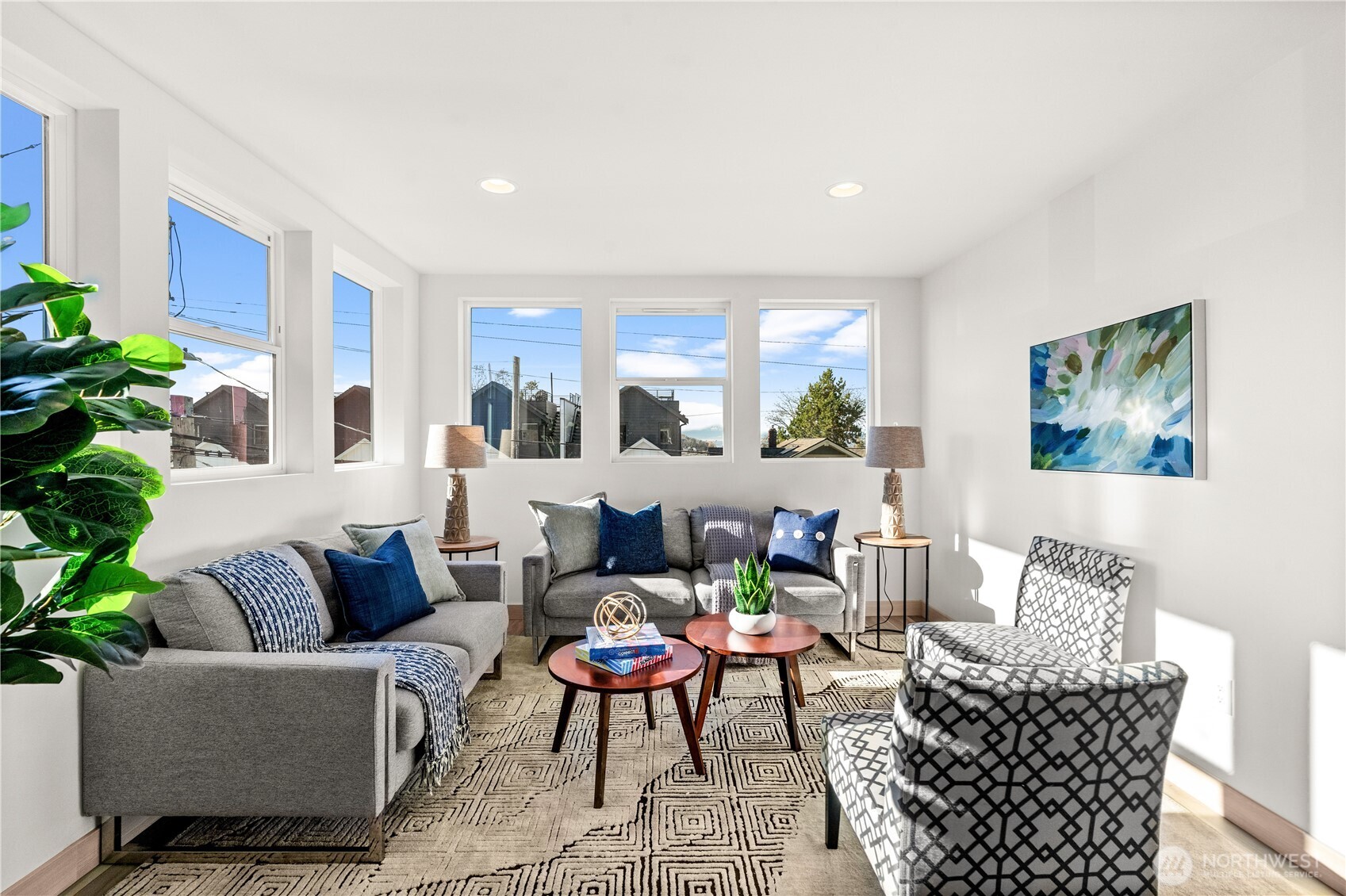 Bright living room with gray sofas, patterned chairs, and large windows.