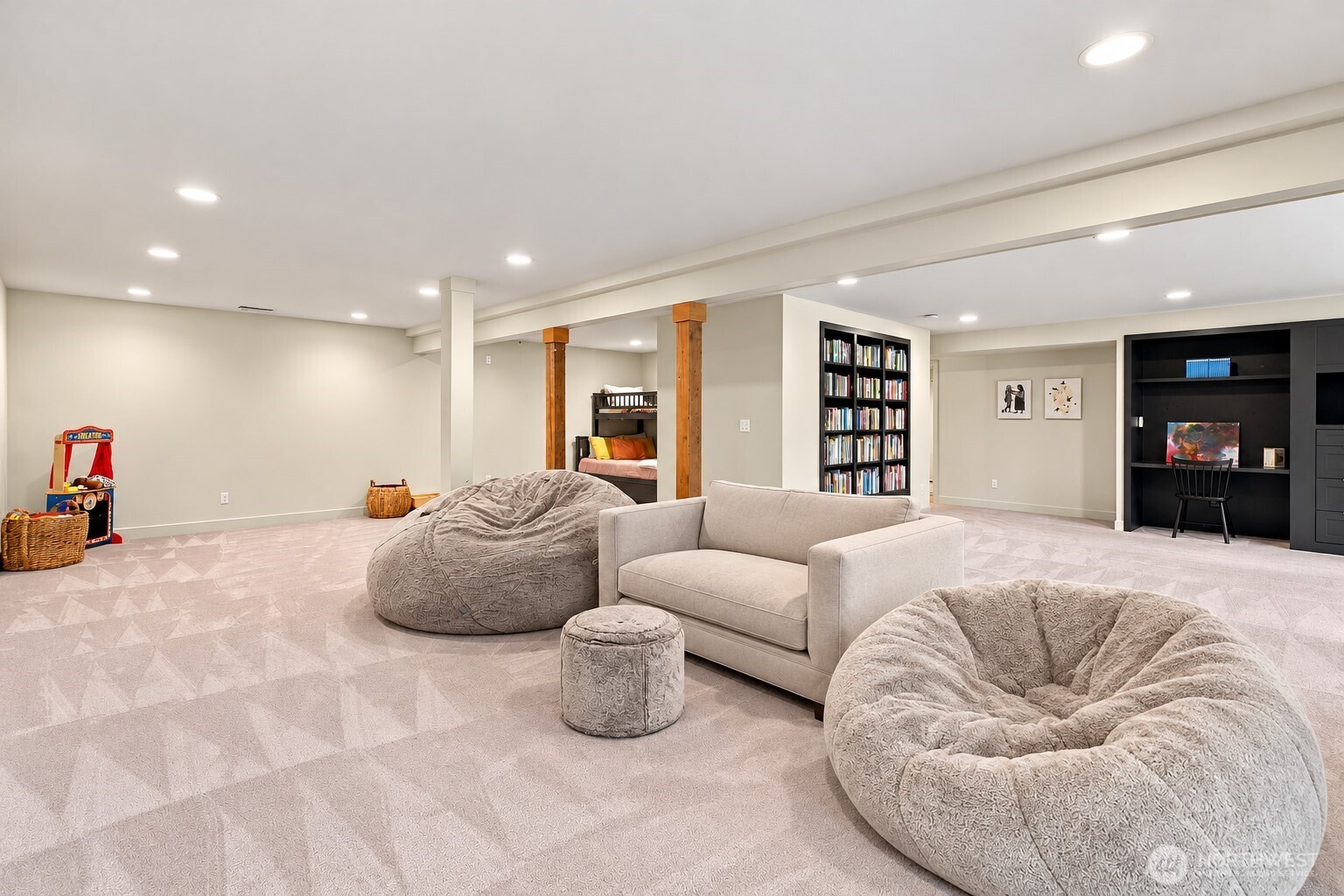 Lower-level recreation room with oversized beanbag chairs, a built-in bookcase and a small bunk-bed nook.