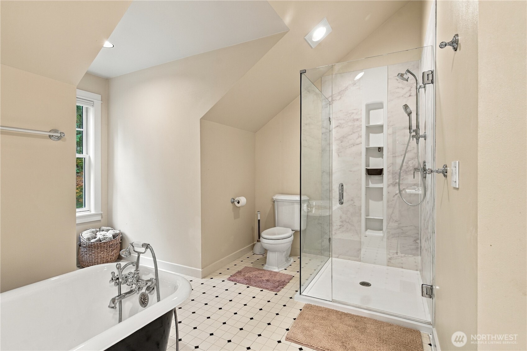 Bathroom with a clawfoot tub, glass shower, marble-look walls, and geometric tile floor.