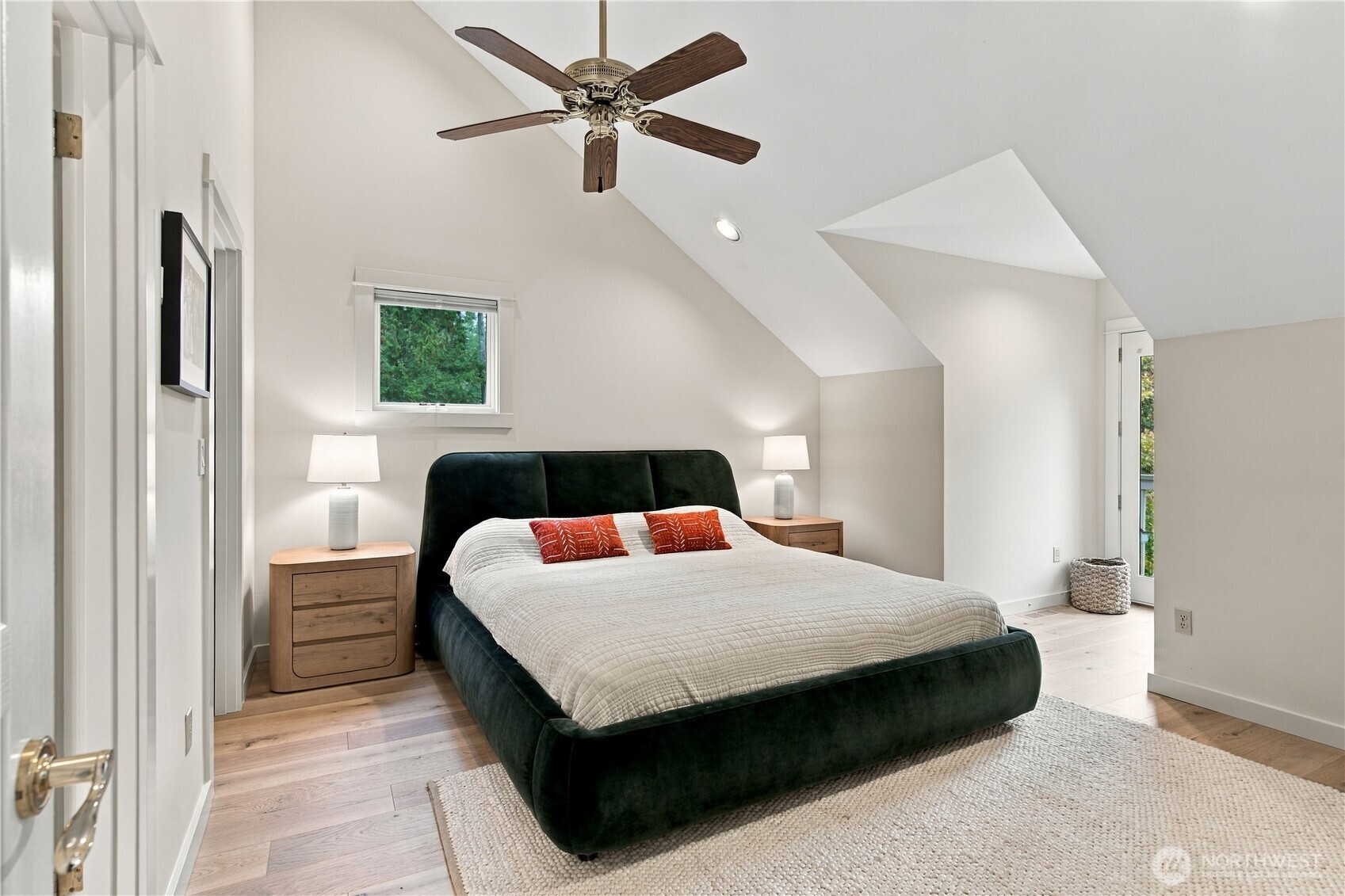 Bedroom with a vaulted ceiling, dark upholstered bed, white bedding, and ceiling fan.