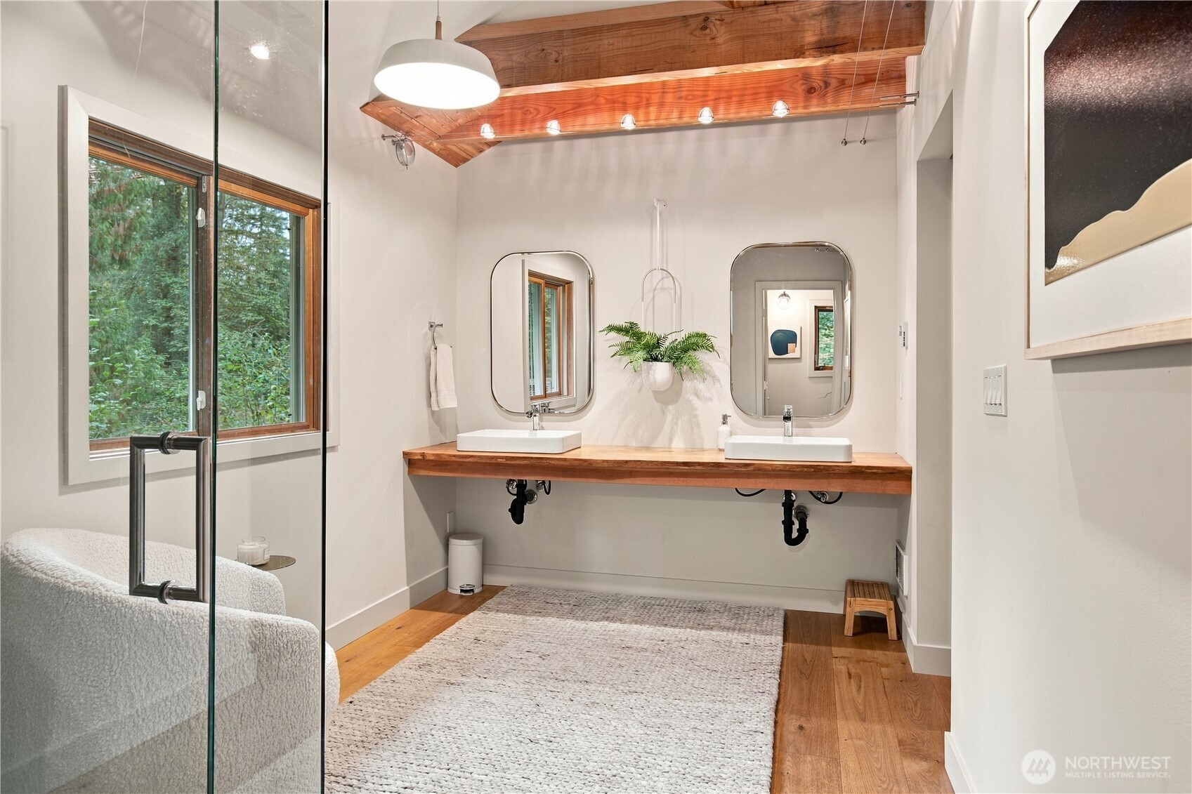 Bathroom with double sinks, a wood vanity countertop, rounded mirrors, and an exposed wood ceiling.