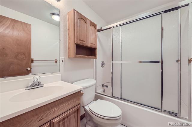 Bathroom with a wood vanity and frosted-glass tub enclosure.