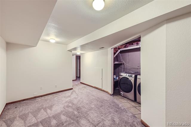 Carpeted room with an open laundry alcove containing a washer and dryer.