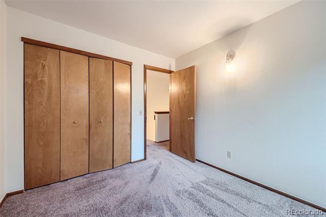 Vacant bedroom with a wood-paneled closet and an open door to the hallway.