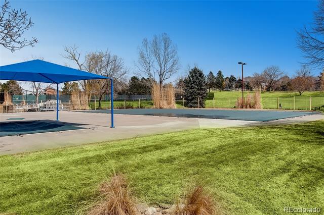 Community recreation area with a blue shade canopy, paved court, and lawn.
