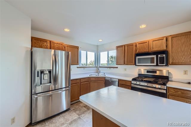 Kitchen with a large white island, wood cabinets, stainless steel appliances, and corner windows.