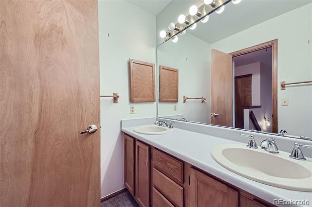Bathroom with a double-sink wood vanity, large mirror, and row of vanity lights.