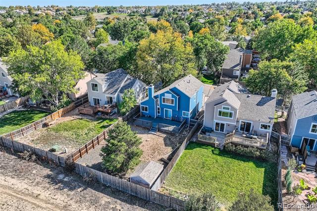 Aerial view of a blue two-story home between neighboring houses, with fenced backyards.