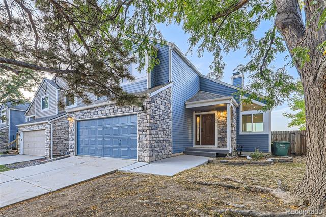 Blue-sided home with stone veneer, two garage doors, and a covered front entry.