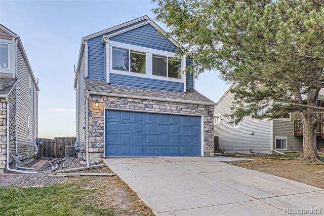 Two-story blue house with a stone facade, blue garage door, and wide concrete driveway.