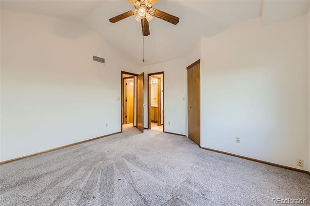 Empty bedroom with gray carpet, wood trim, and a ceiling fan.