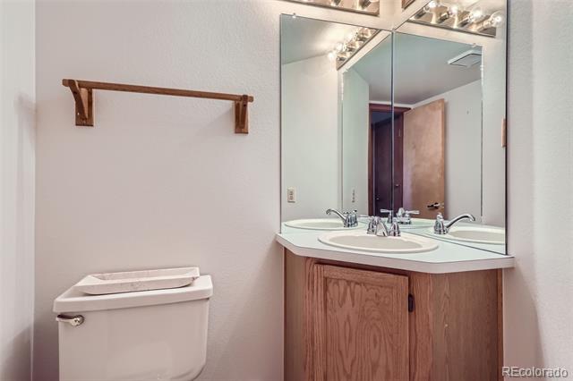 Bathroom with a wood vanity, large mirror, and toilet.