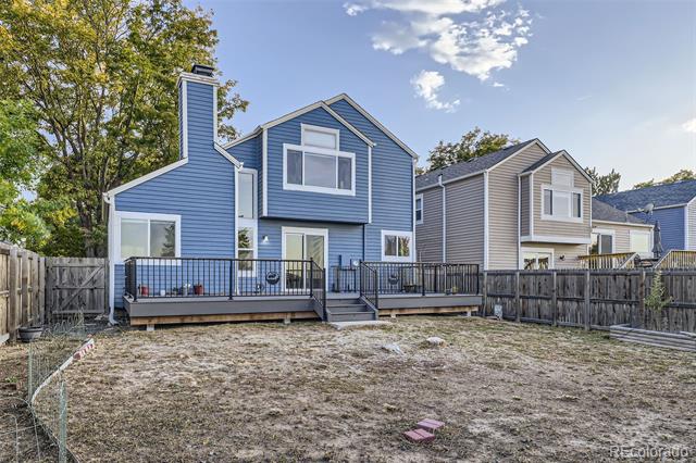 Blue two-story house with a raised deck overlooking a fenced backyard.