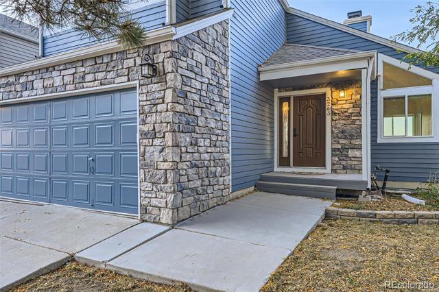 House exterior with blue siding, stone facade, garage, and covered front entry.