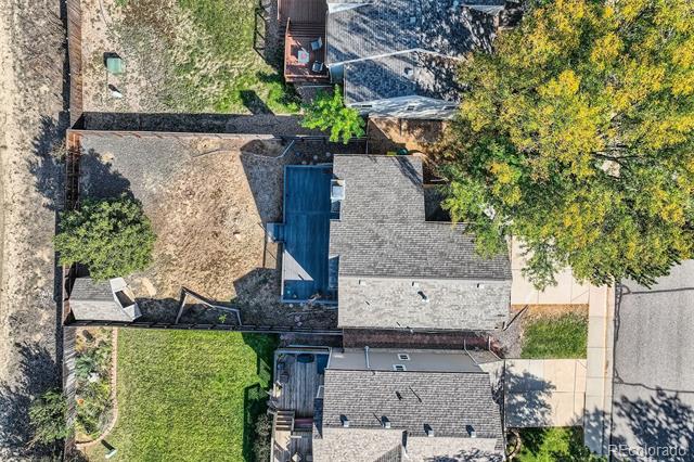 Aerial view of the home with a blue pool, fenced yard, and mature trees.