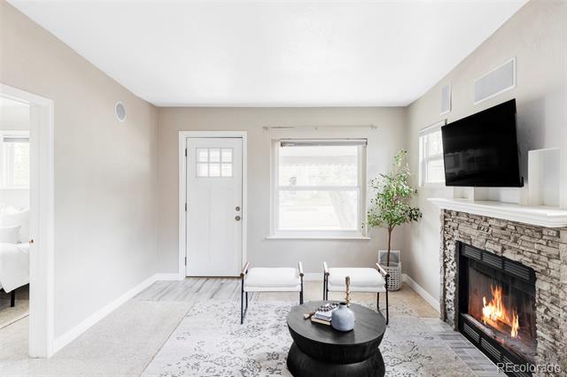 Living room with a stone fireplace, mounted television, and two chairs around a round coffee table.