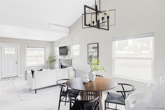 Open-plan living and dining room with vaulted ceiling, fireplace, and dark wood dining table.