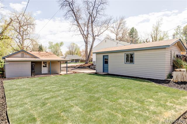 Rear of a single-story home with a broad lawn, detached garage, and separate outbuilding.