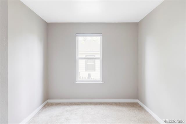 Empty bedroom with pale carpet and a centered window.