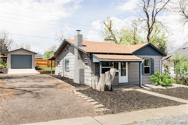Single-story gray house with a covered porch, wide driveway, and detached garage.