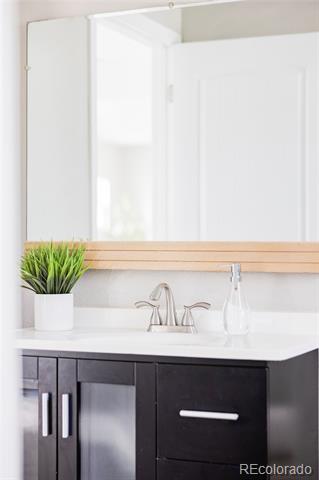 Bathroom vanity with dark cabinets, a wide mirror, and a small potted plant.