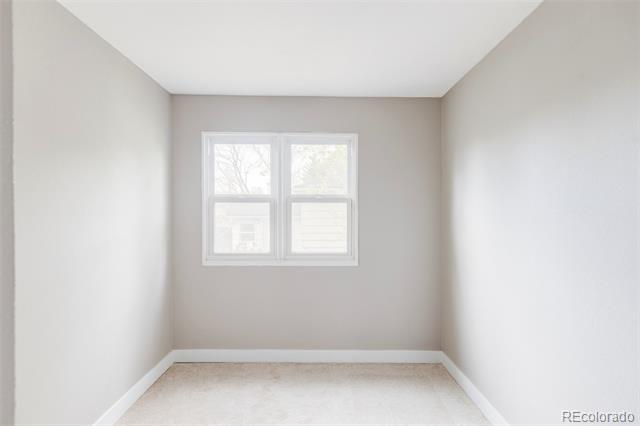 Empty room with beige carpet and a double window on the far wall.