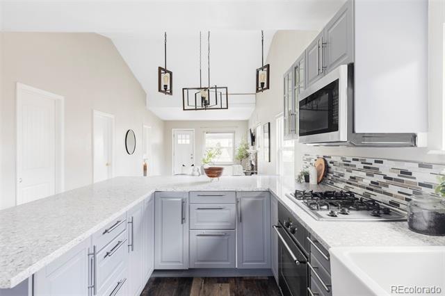 Bright kitchen with gray cabinets, white stone counters, a large island, and stainless steel appliances.