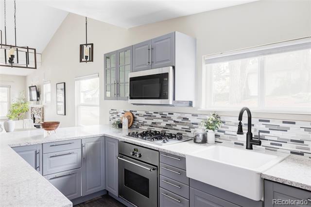 Kitchen with gray cabinetry, a white farmhouse sink, and a mosaic tile backsplash.