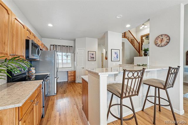 Kitchen with wood cabinets, stainless steel appliances, and a breakfast bar with tall stools.