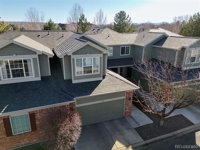 Two-story gray-and-brick house with a two-car garage, viewed from above the front yard.