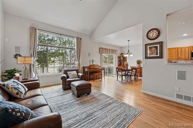 Furnished living room with leather seating, a large window, and an open dining area.