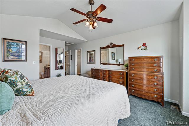 Bedroom with a white quilted bed, wooden dressers, and a ceiling fan with lights.