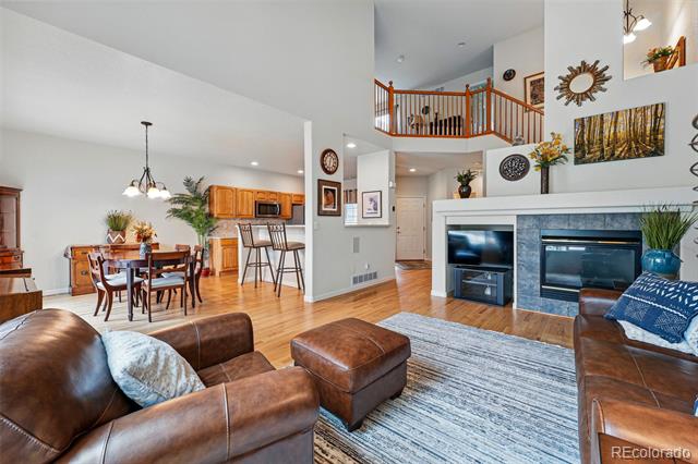 Living room with leather seating, stone fireplace, and loft railing overlooking the open dining area.