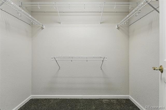 Empty walk-in closet with white wire shelving and gray carpet.