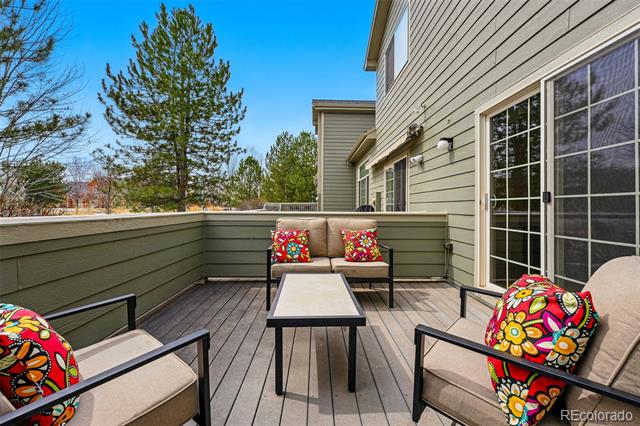 Furnished deck with cushioned seating, colorful floral pillows, and sliding glass doors.