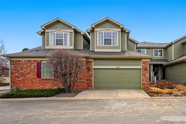 Two-story home with a red brick facade, olive-green siding, and a two-car garage.